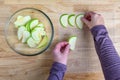 WomanÃ¢â¬â¢s hands taking granny smith apple slices out of a glass bowl and laying them out on a mesh tray for dehydrating Royalty Free Stock Photo